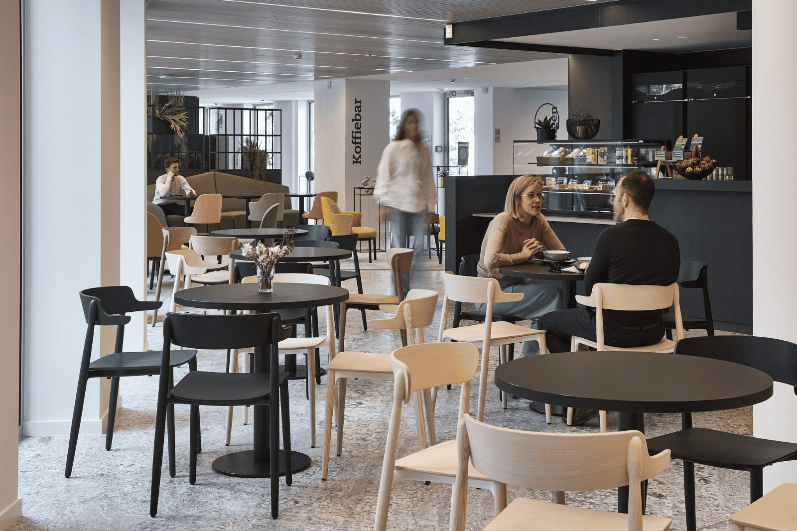 Cantine d'entreprise avec bar à café et mélange de chaises claires et foncées