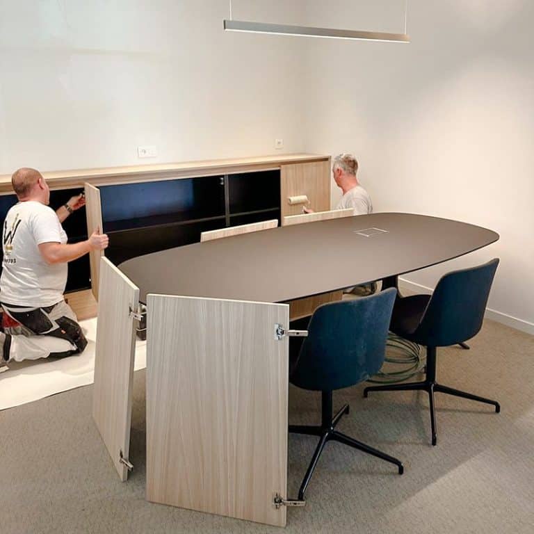 Monteurs plaatsen het laatste meubilair tijdens de oplevering van een nieuw kantoor