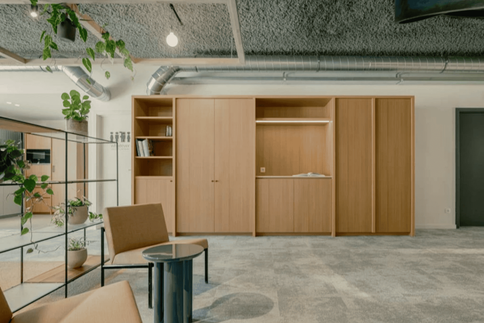 Loungehoek met houten kasten en veel groen in een modern kantoor