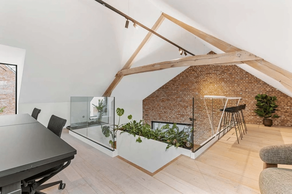 Open coworkingruimte onder houten balken met zitplekken, groene accenten en duurzame materialen, ontworpen door Buro Project