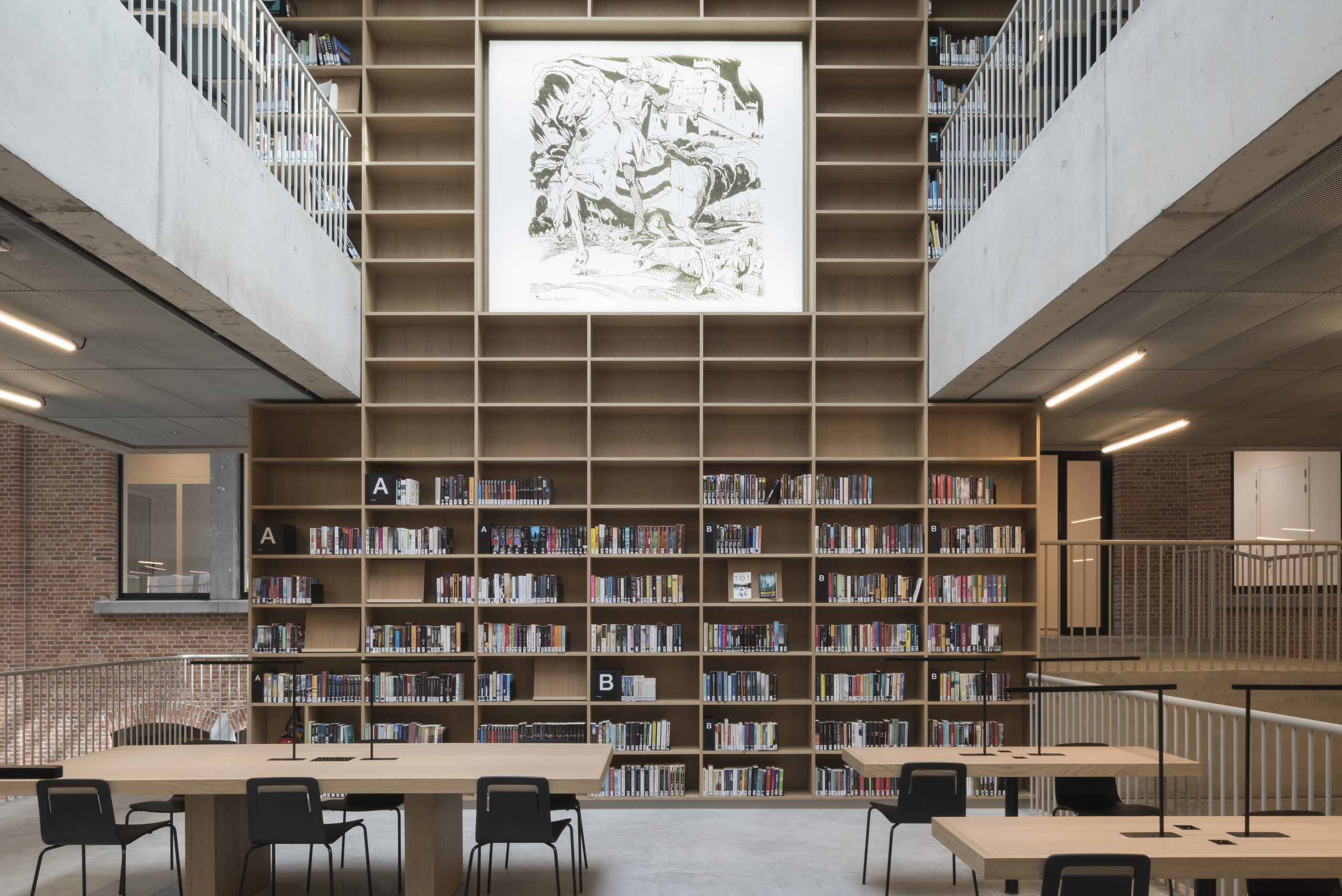 Open en lichte overheidsbibliotheek met hoge boekenwand en flexibele werkplekken ingericht door Buro Project
