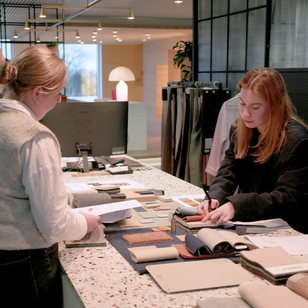 Kantoorinrichting met een adviesgesprek waarbij stalen en materialen voor de werkplek worden besproken