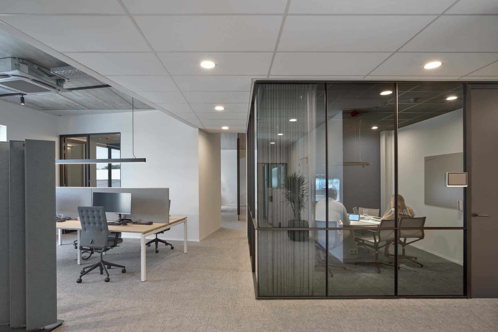 Akoestisch geoptimaliseerde vergaderruimte in een farmaceutisch kantoor met glazen wanden, gordijnen en een rustige, professionele uitstraling