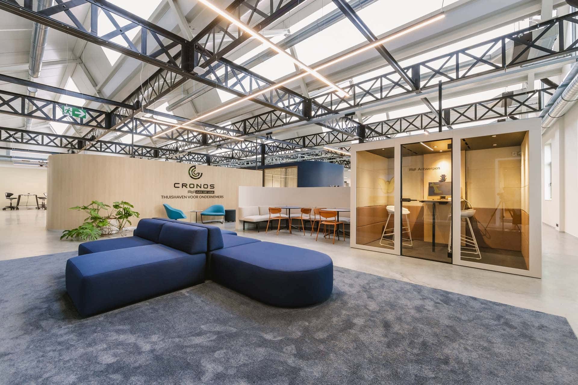 Open kantoorruimte met loungezit, vergaderpods en branding die de identiteit van het bedrijf zichtbaar en voelbaar maakt