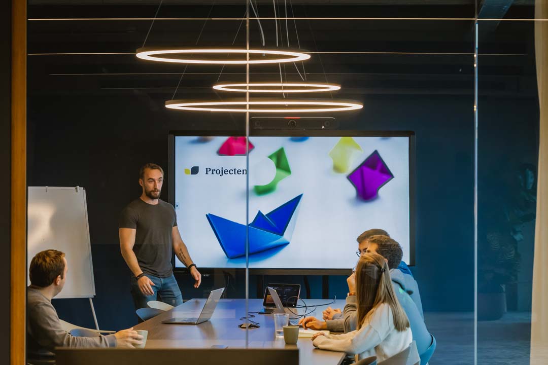 Vergaderruimte met presentatie op groot scherm waar collega’s geconcentreerd samenwerken in een afgesloten focusplek